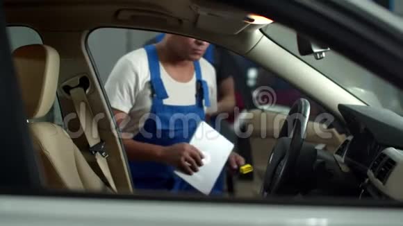 带着平板电脑的机械师走进一辆车告诉同事做笔记视频的预览图