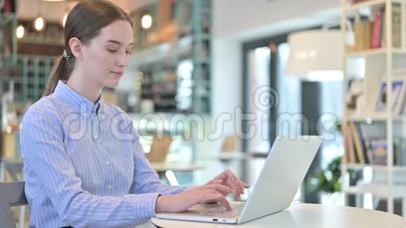 年轻女商人在咖啡馆里对着摄像机微笑时使用笔记本电脑视频的预览图