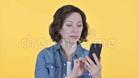 智能手机丢失的老妇人黄色背景视频的预览图
