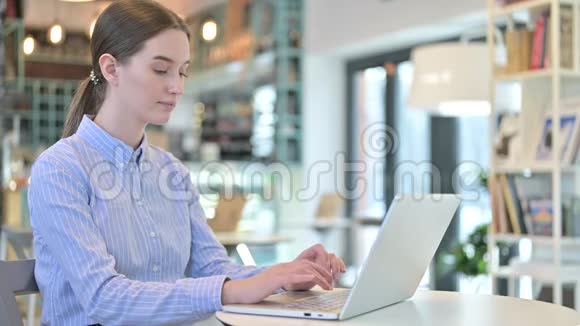 年轻女商人在咖啡馆里看摄像机时使用的笔记本电脑视频的预览图