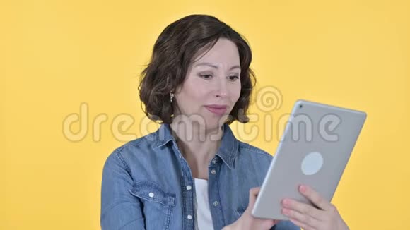 一位使用黄色背景平板电脑的老妇人视频的预览图