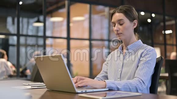 有脊背疼痛的妇女在笔记本电脑上工作视频的预览图