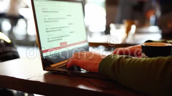 贴身男手自由职业者坐在咖啡馆工作笔记本电脑视频的预览图