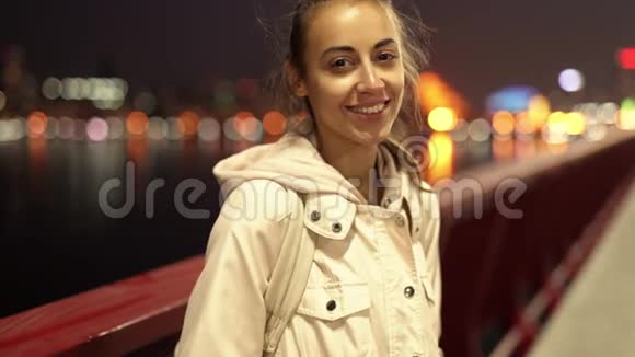特写慢镜头美丽微笑的年轻女子走在户外的夜晚城市视频的预览图