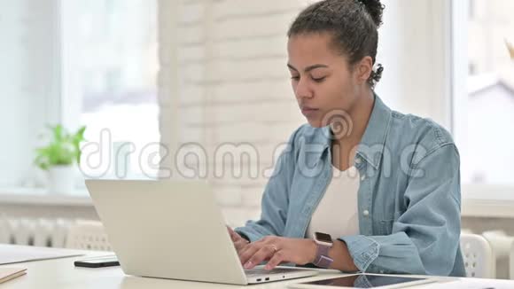 年轻的非洲妇女在笔记本电脑上工作视频的预览图