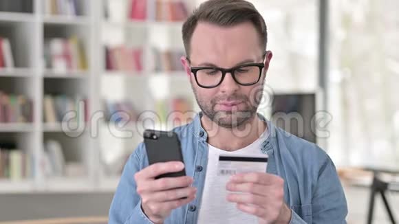戴眼镜的年轻人在智能手机上网上购物视频的预览图