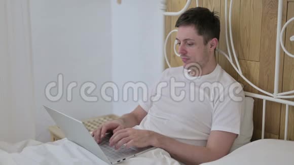 勤劳的年轻人在床上工作视频的预览图