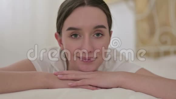 亲近快乐的年轻女人在床上做大拇指视频的预览图