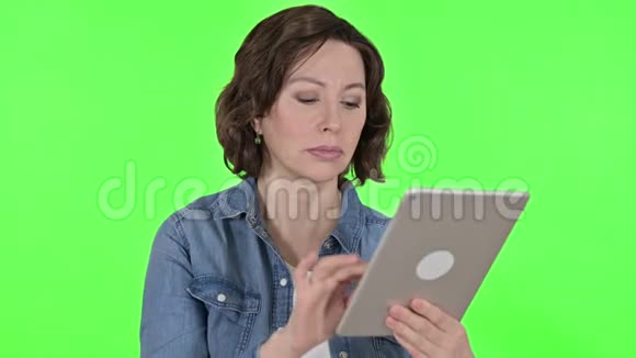 使用数码平板电脑的老女人使用绿色彩色钥匙背景视频的预览图