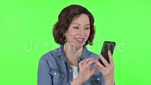 老女人使用智能手机的绿色彩色钥匙背景视频的预览图