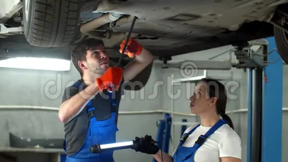 戴手套的机械师修理汽车女人拿着手电筒视频的预览图