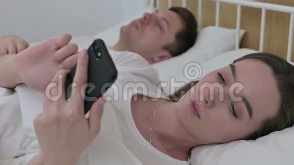 女人在床上用智能手机应对失败视频的预览图