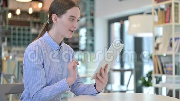 年轻女商人在咖啡馆的平板电脑上庆祝成功视频的预览图