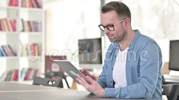 工作时戴眼镜的年轻人用平板电脑视频的预览图