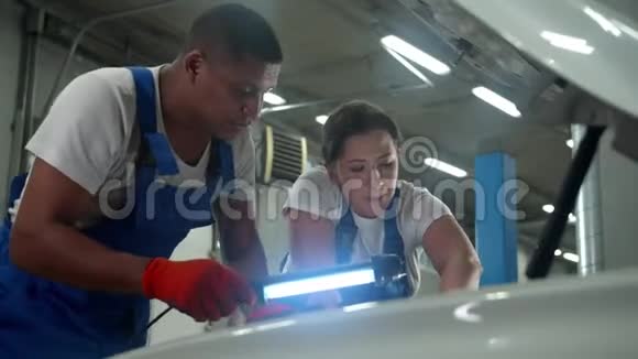 机械师拿着手电筒穿制服的女人修理汽车视频的预览图