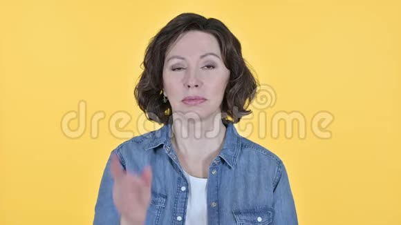 不黄色背景上的老女人的手指标志视频的预览图