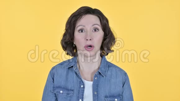 黄色背景下的老妇人震惊的表情视频的预览图