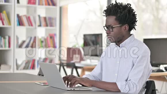 生病咳嗽的非洲男人在笔记本电脑上工作视频的预览图
