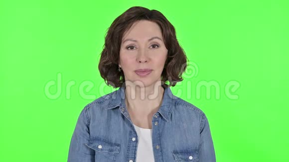老女人在镜头前挥舞着绿色彩色钥匙背景视频的预览图