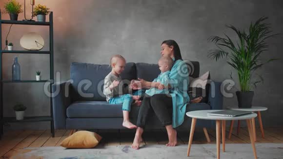 年轻的母亲和孩子们在沙发上玩耍幸福的家庭家庭舒适视频的预览图