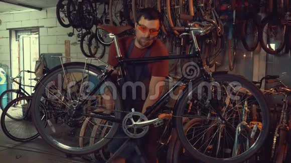 主题小企业自行车修复戴着安全护目镜手套和围裙的年轻白种人黑发男子使用手工工具视频的预览图