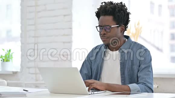 非洲青年男子在办公室的笔记本电脑上失败视频的预览图