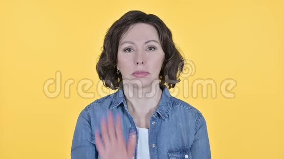 在黄色背景下停止老妇人的手势视频的预览图