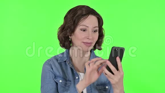 老妇在智能手机上庆祝绿色彩键背景视频的预览图