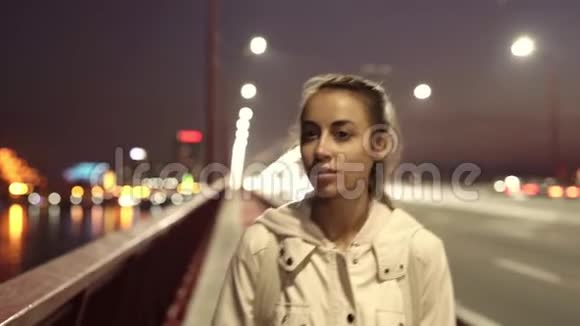 慢动作的美丽微笑的年轻女子走在户外的夜晚城市视频的预览图