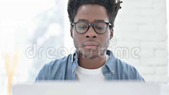 非洲青年男子在笔记本电脑上震惊的肖像视频的预览图