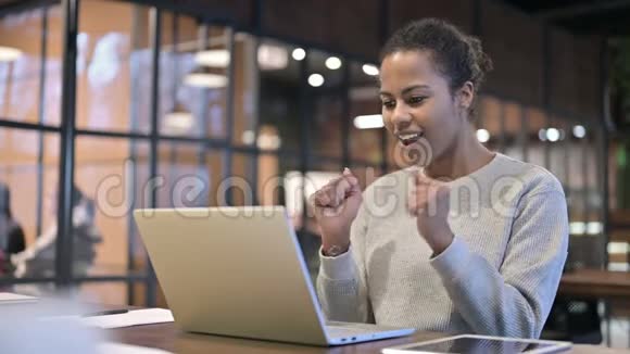 兴奋的非洲妇女在笔记本电脑上庆祝成功视频的预览图
