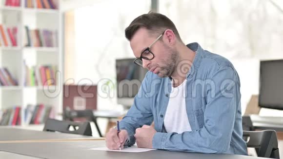 戴眼镜写纸的年轻人视频的预览图