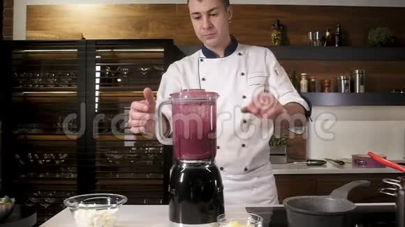 在厨房的搅拌机里做冰沙厨师把浆果酱倒进锅里视频的预览图