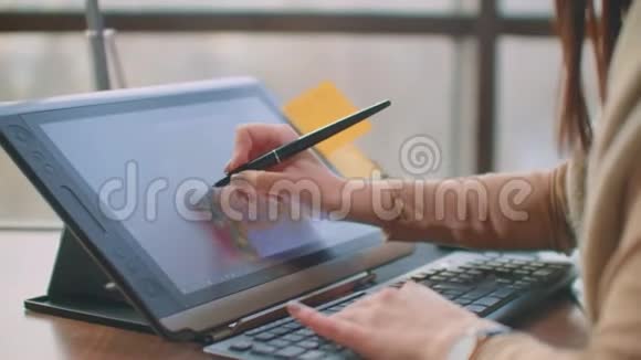 年轻的女人坐在她的办公桌前她在画画写作用钢笔与数字平板电脑手拿笔视频的预览图