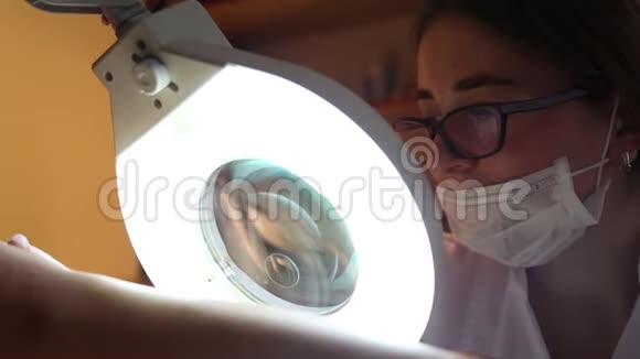 皮肤科医生通过美容灯的放大镜检查年轻人身体上的皮肤美容视频的预览图