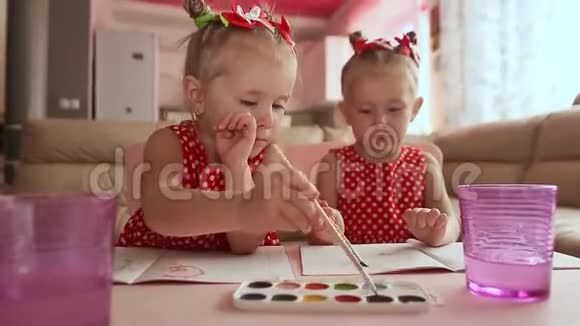 两个小妹妹双胞胎很高兴和坐在桌子旁的水彩画视频的预览图