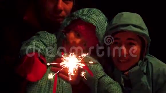 一个幸福的家庭缓慢地举着孟加拉火在夜晚闪耀视频的预览图