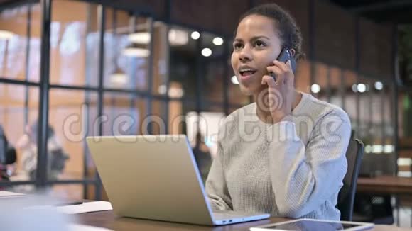 非洲妇女在电话和笔记本电脑上交谈视频的预览图