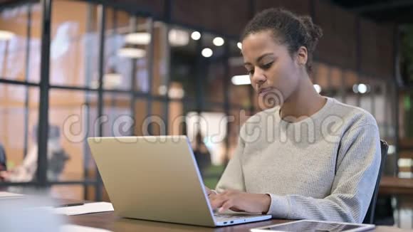 头痛的非洲妇女在笔记本电脑上工作视频的预览图