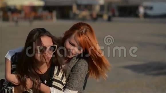 两个女朋友年轻的女朋友在度假时背着背在城市里欢笑和散步晴天视频的预览图