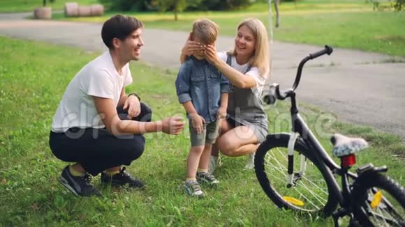慈爱的父母正在给小儿子一个惊喜闭上眼睛给他一辆新自行车快乐的男孩视频的预览图