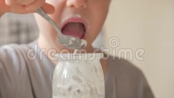 小男孩坐在桌子旁独自用勺子吃婴儿食品一个23岁的男孩急切地吃牛奶视频的预览图