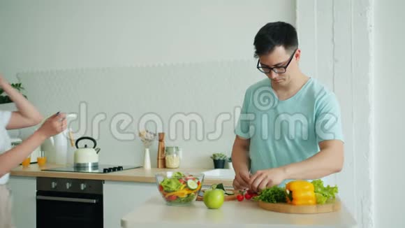 男人丈夫在厨房做饭当幸福的女孩带着怀孕测试视频的预览图