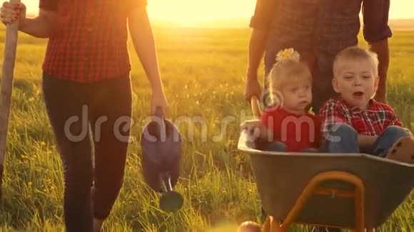 一家农民在日落时分手里拿着工具和孩子们在新鲜空气中散步坐着的小孩视频的预览图