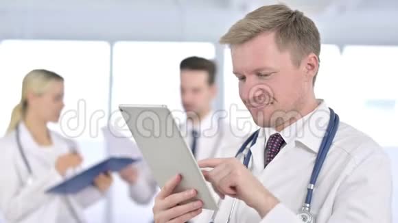 具有吸引力的男性医生在办公室使用平板电脑的画像视频的预览图