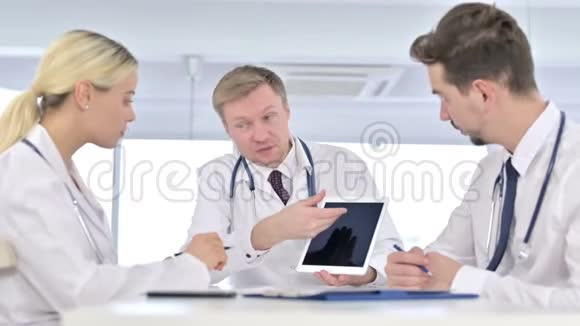严重男性医生与同事讨论有关平板电脑的报告视频的预览图