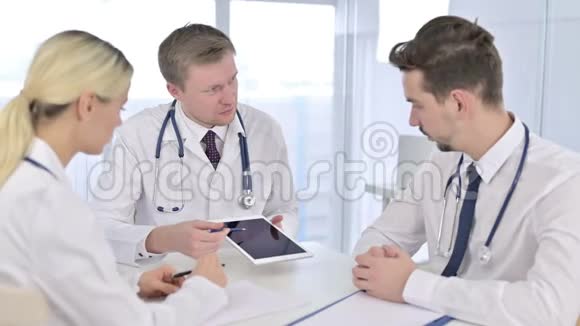 严重男性医生与同事讨论有关平板电脑的报告视频的预览图