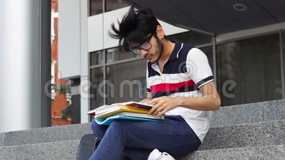 亚洲学生男子坐在楼梯上看书视频的预览图