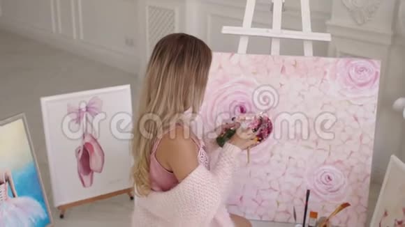 一位穿着粉红色毛衣的女画家画了一幅坐在地板上的房子的照片视频的预览图