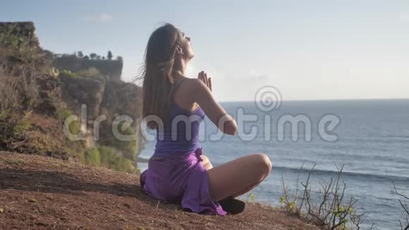 适合年轻女性在山上为海洋练习太阳敬礼瑜伽年轻女性享受冥想和瑜伽健身健身视频的预览图